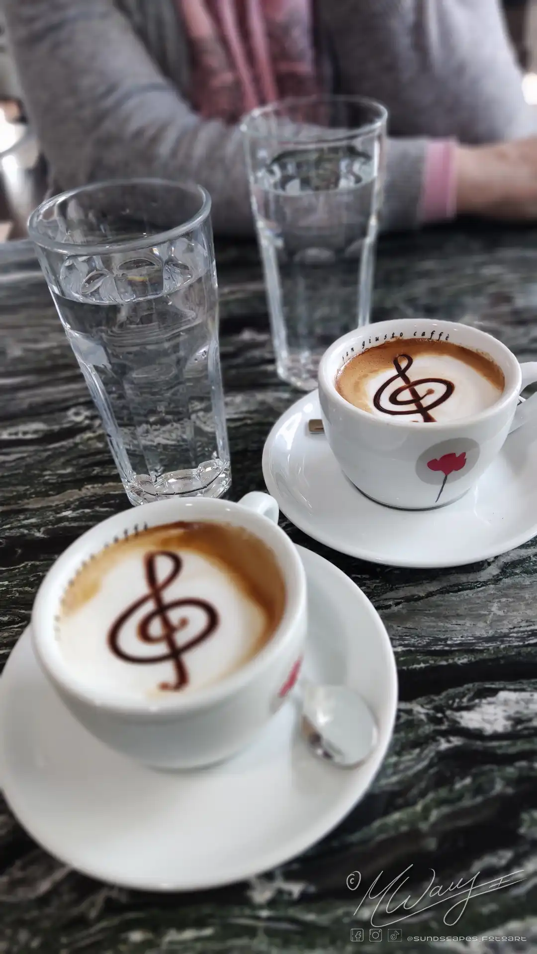 two cups of coffee with a music symbol on the foam