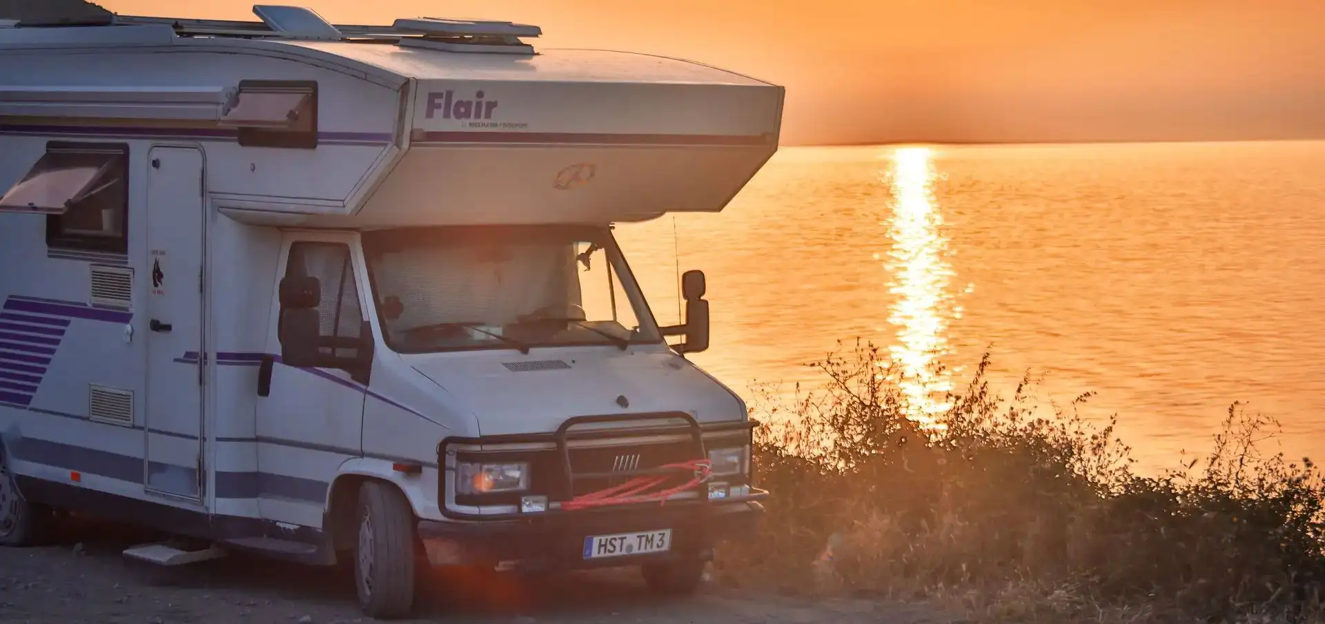 a camper van parked on a road next to the ocean. Vanlife-Abenteuer