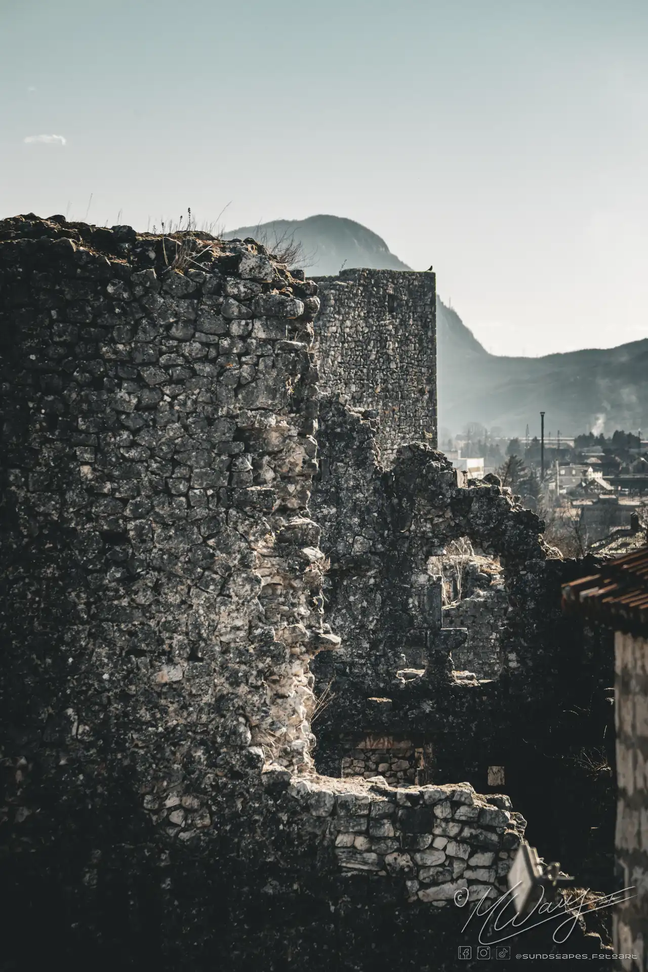 a stone wall with a city in the background