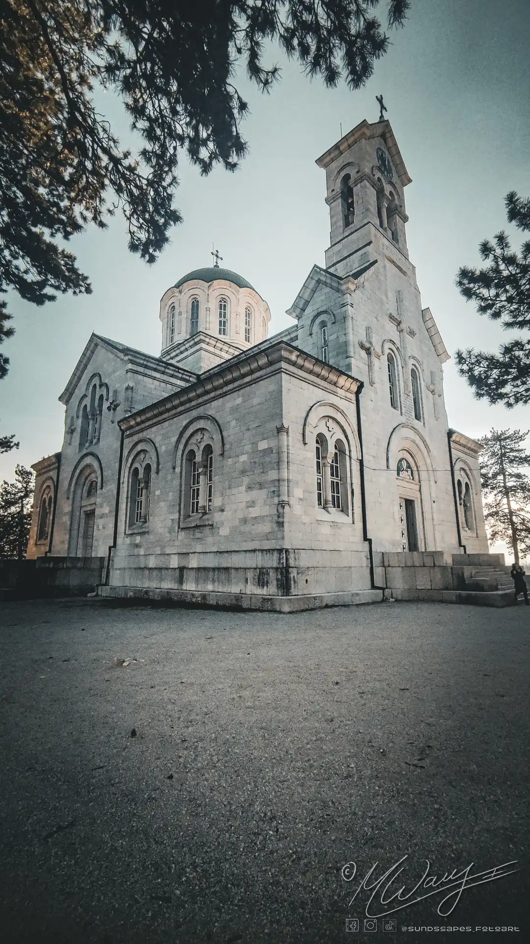 a stone building with a steeple and a person standing in front of it