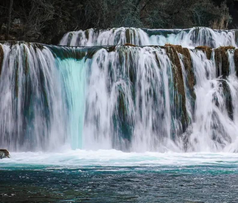 a waterfall with trees around it im Krka Nationalpark Kroatien