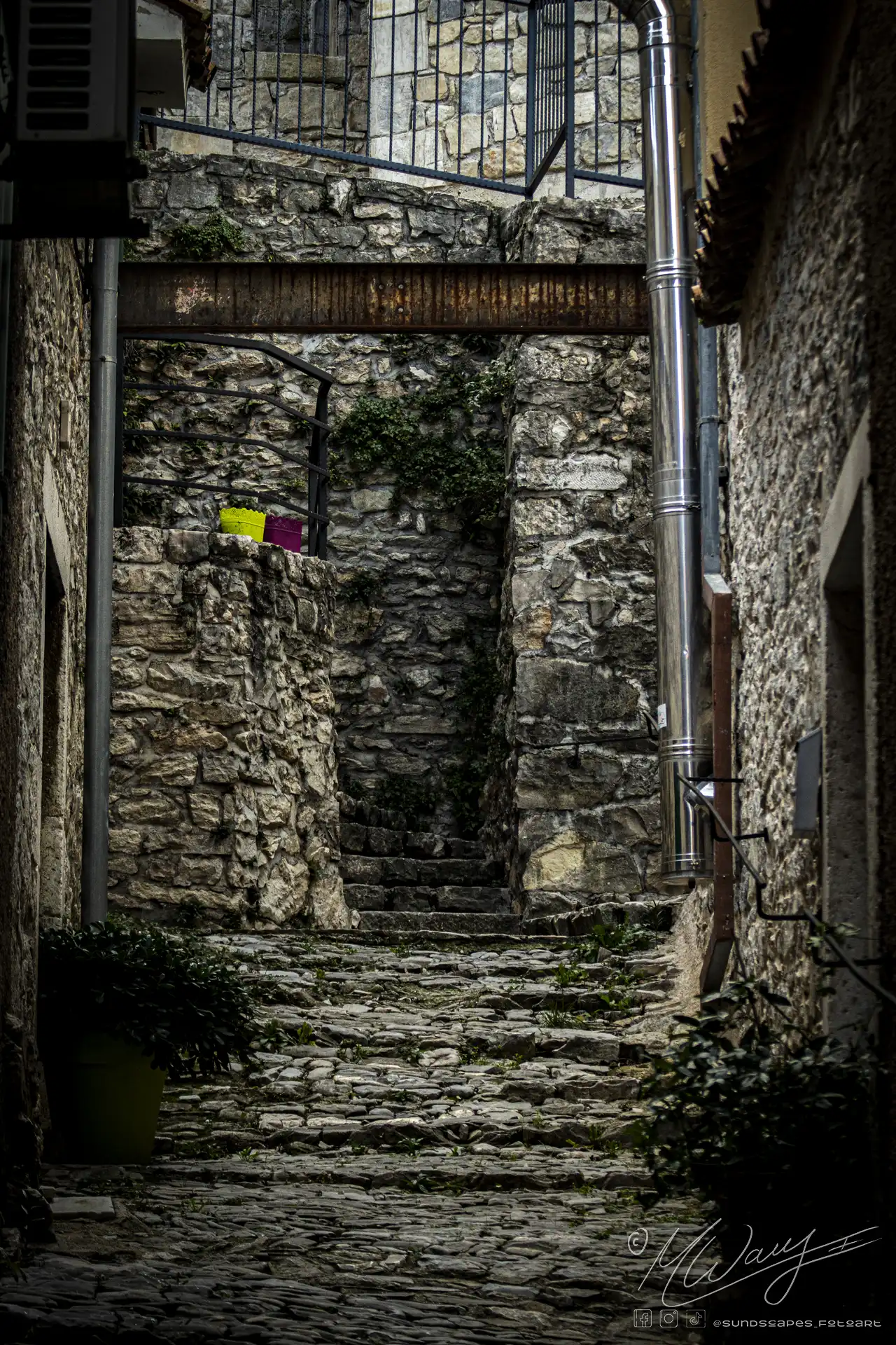 a stone alley way with a metal structure and plants