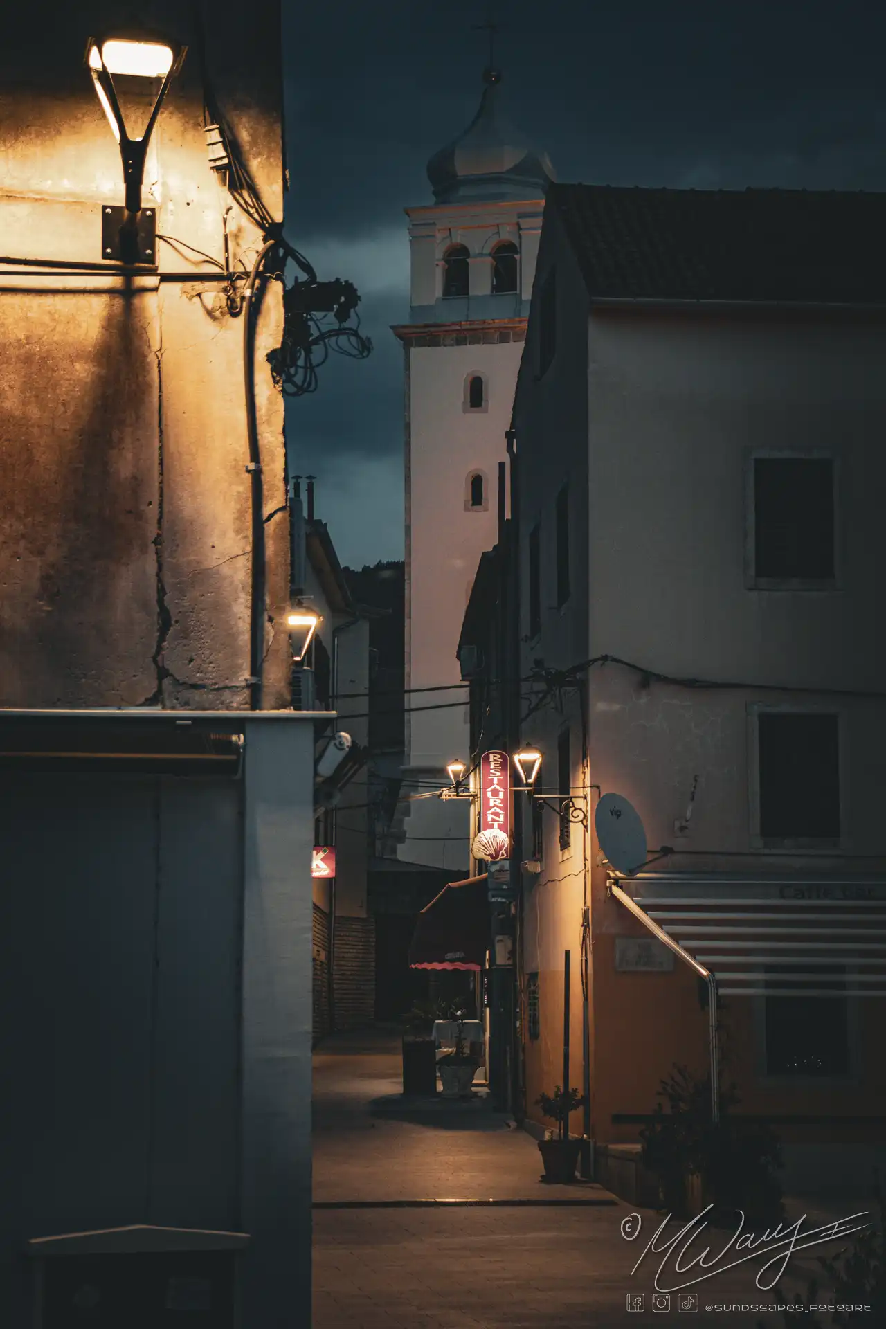 a dark alleyway with a tower and a building