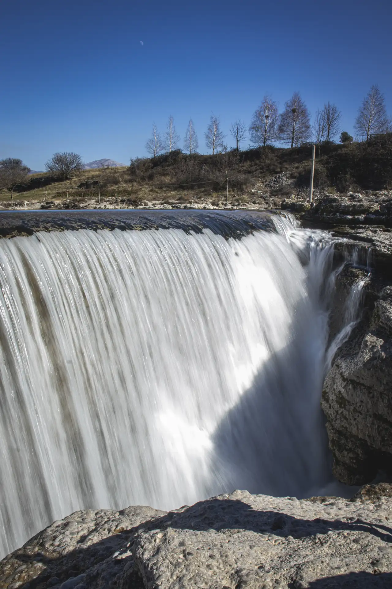 a waterfall over rocks with trees in the background