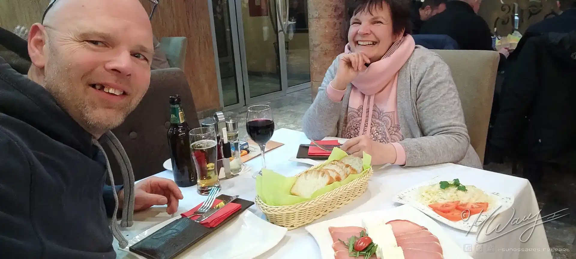 a woman laughing at a table with food and drinks