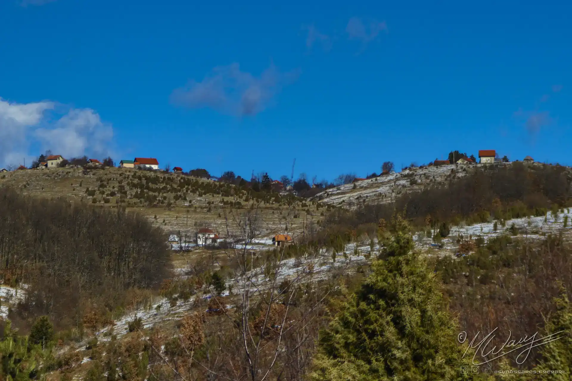 a snowy hillside with houses and trees