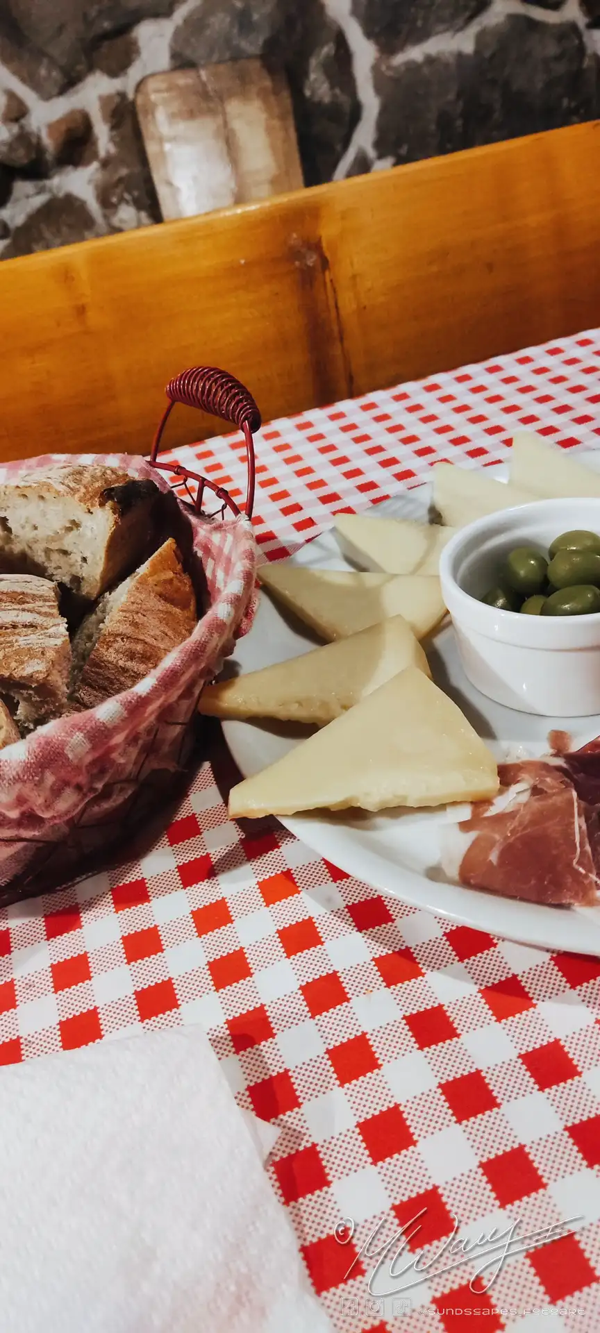 Bread in basket, and a platter of starters, olives, cheese and ham