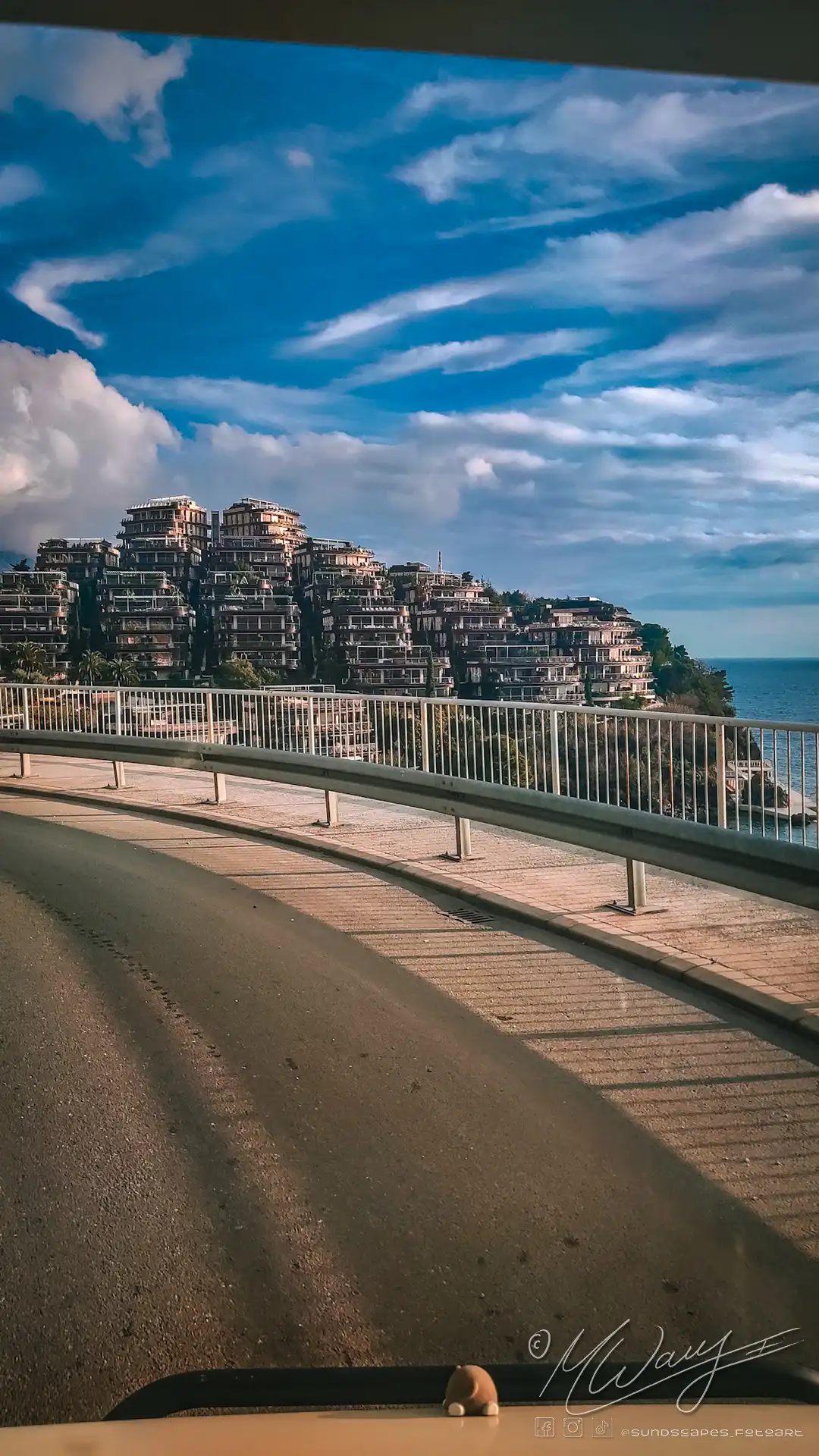 a road with a fence and buildings on a hill