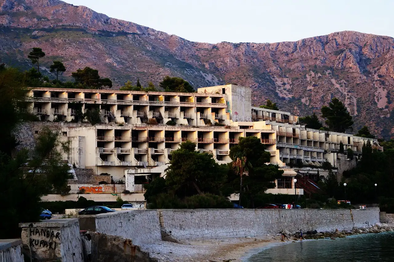 an abandoned hotel building with many windows and trees on the side of a beach