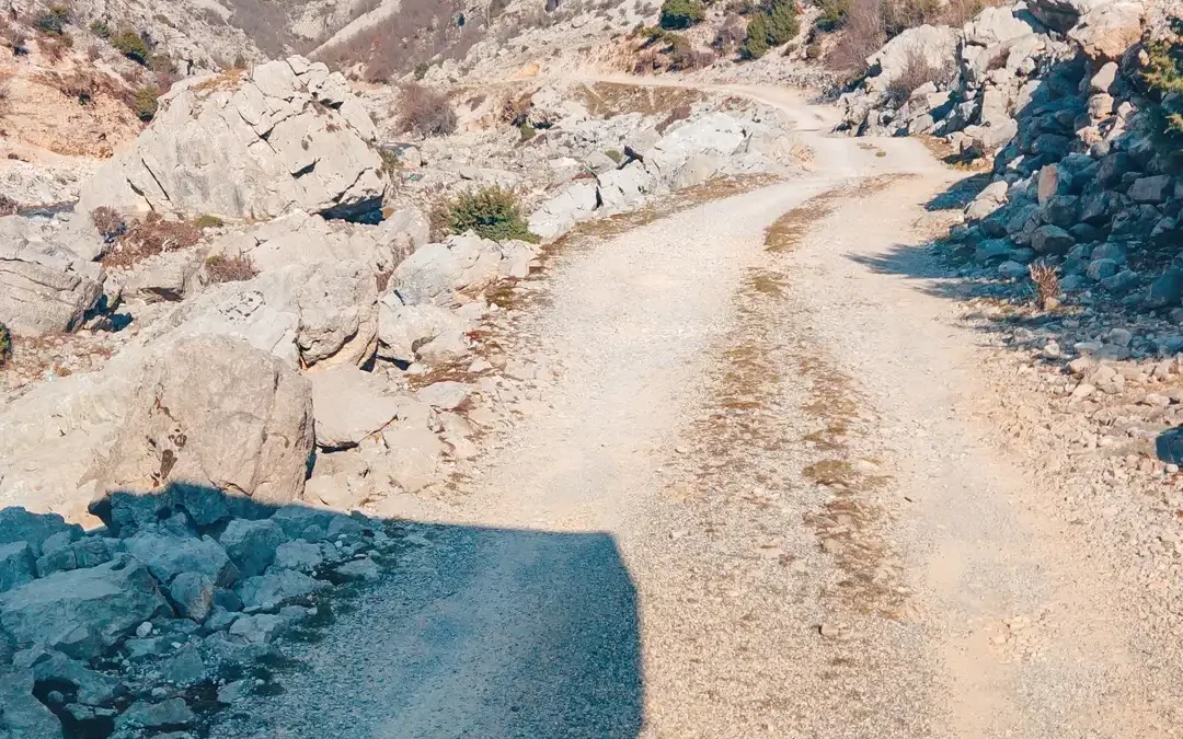 a dirt road with rocks and mountains in the background - Offroad im Camper