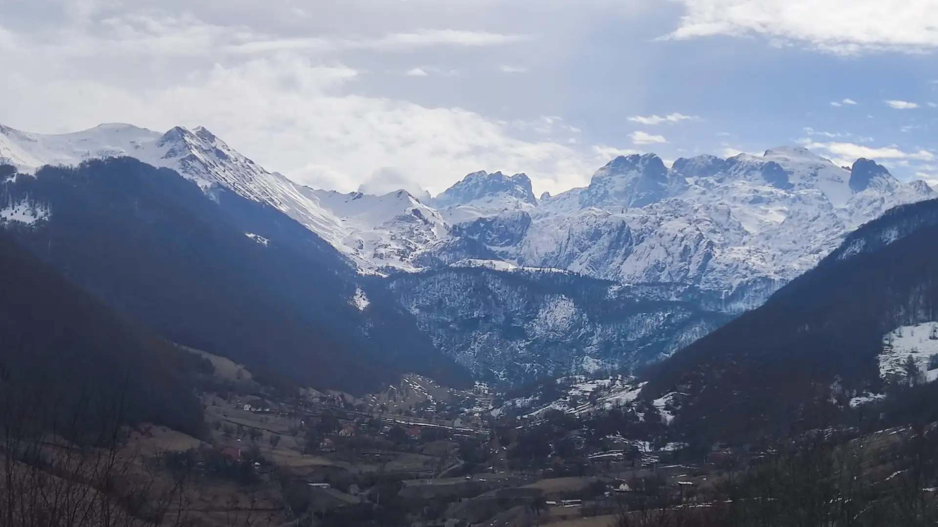 a snowy mountain range with a town in the distance in Albanien